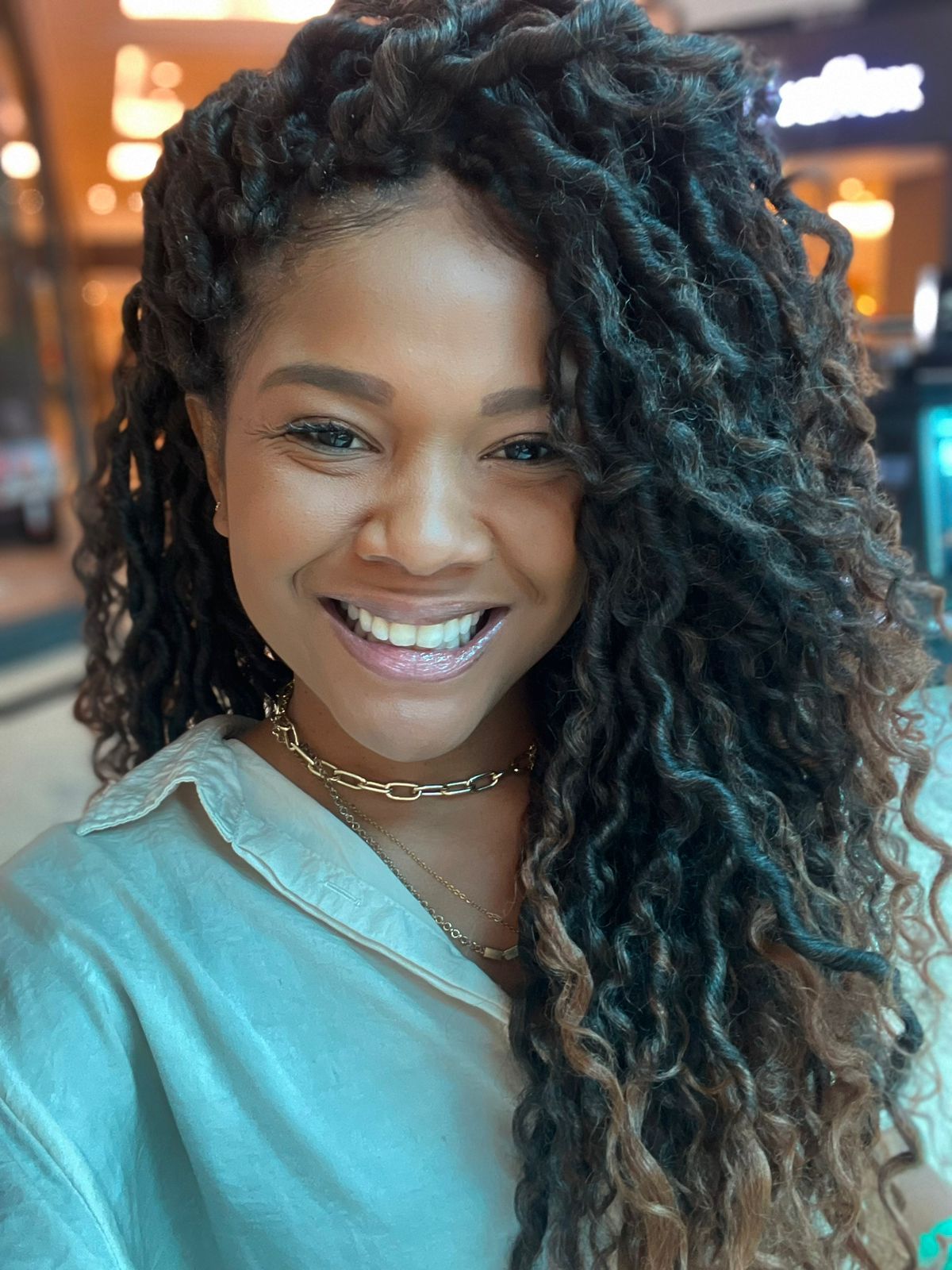 Imagem de Dandara Maria Barbosa. Ela tem cabelos cacheados e usa uma camisa com tonalidade bege. Ela aparece sorrindo na foto.