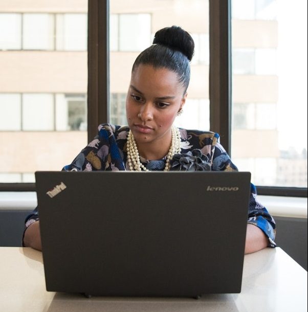 Imagem de uma mulher usando um notebook em um escritório. A imagem foi escolhida para ilustrar o texto sobre o edital Novos Caminhos.